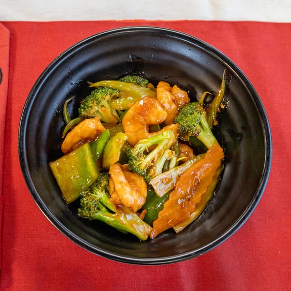 A black bowl filled with China Bell's shrimp, broccoli, and green peppers in a savory sauce.